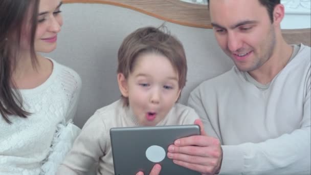 Jeune famille heureuse utilisant une tablette sur le canapé — Video
