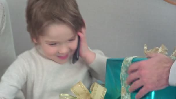 Un niño hablando por teléfono describiendo los regalos que recibió para Navidad. — Vídeos de Stock