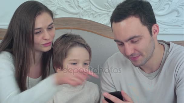 Feliz joven familia sentada en el sofá con el padre usando el teléfono — Vídeos de Stock