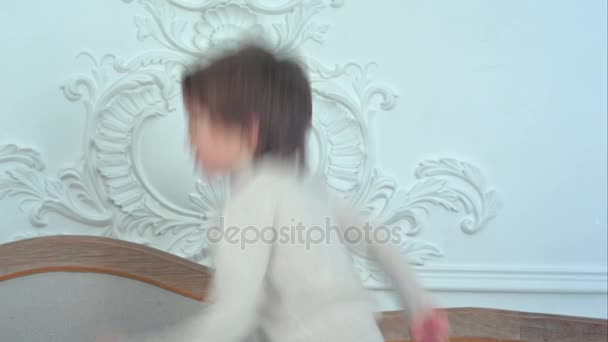 Little boy joyfully jumping on a sofa — Stock Video