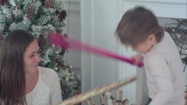 Mutlu anne ve oğlu kağıt kılıç kaydırma sahip Noel ağacının yanında mücadele