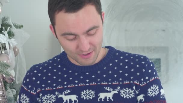 Jeune homme en pull tricoté avec des cerfs lisant conte de Noël — Video