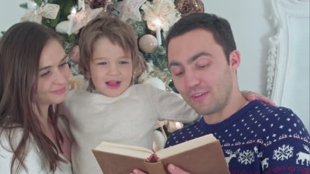 Familia feliz de tres leyendo juntos en la noche de Navidad — Vídeo de stock