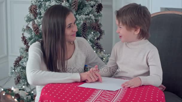 Счастливая мать и ее сын пишут письмо Санте — стоковое видео