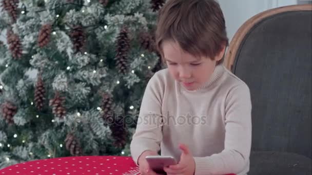 Gelukkig jongetje met behulp van slimme telefoon thuis ingericht voor Kerstmis — Stockvideo