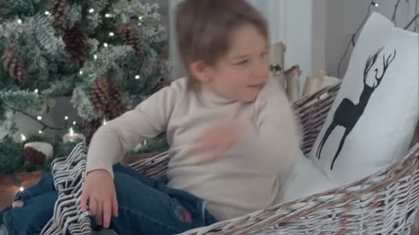 Niño arreglando almohadas de Navidad en su trineo de mimbre — Vídeos de Stock