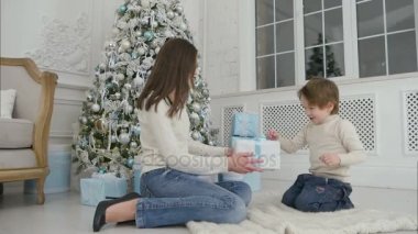 Küçük bir çocuk ve onun anne sallayarak Noel mevcut içinde whats tahmin etmeye çalışıyorum heyecanlı