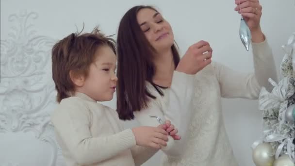 Lächelnde Mutter und ihr Sohn schmücken den Weihnachtsbaum im Wohnzimmer — Stockvideo