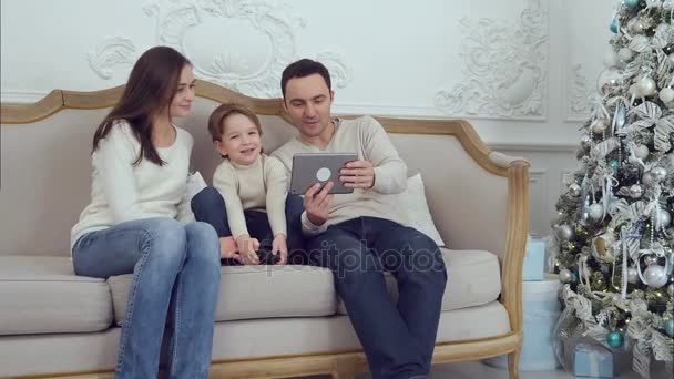 Joven familia feliz usando la tableta en el sofá — Vídeos de Stock