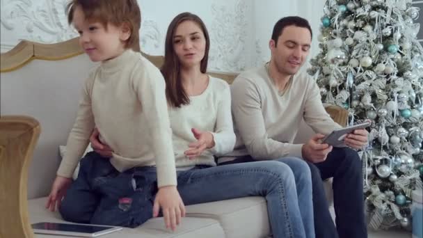 Junge Mutter spielt mit ihrem energiegeladenen kleinen Sohn, während Papa Tablette benutzt — Stockvideo