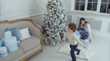 Anne ve küçük oğlu hediyeler Noel ağacının altına koyarak