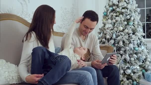 Anak kecil berbaring di pangkuan ibu dan mengalihkan perhatian ayahnya dari tablet — Stok Video