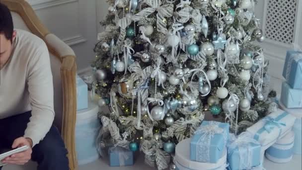 Happy family using tablet PC on sofa with Christmas tree in the background — Stock Video