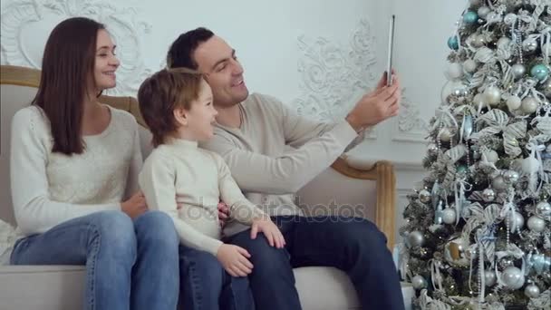 Jovem família feliz tomando selfies no sofá com tablet — Vídeo de Stock