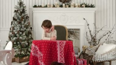 Sevimli küçük çocuk Chirstmas ağaç arka plan üzerinde evde büyük bir koltukta otururken Noel Baba arıyor