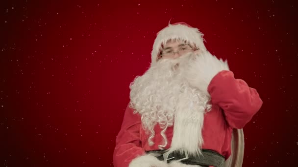 Santa Claus volání mobilním telefonem na červeném pozadí se sněhem — Stock video