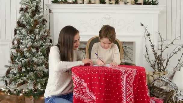 Genç anne küçük oğlu Noel Baba'ya bir mektup yazmak için yardım — Stok video