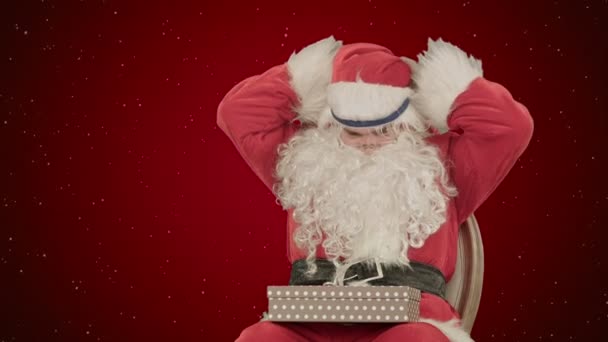 Santa Claus sosteniendo regalos de Navidad sobre fondo rojo con nieve — Vídeo de stock