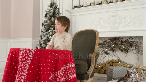 Schattige kleine jongen denken wat te schrijven in zijn brief aan de Kerstman — Stockvideo