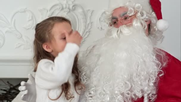 Doce menina no colo do Papai Noel dizendo-lhe o que ela quer para o Natal — Vídeo de Stock
