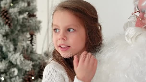 Doce menina sentada no colo do Papai Noel descrevendo o que ela quer presentes para o Natal — Vídeo de Stock