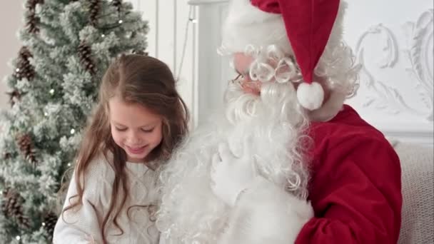 Litlle menina sacudindo seu presente de Papai Noel tentando adivinhar o que está dentro — Vídeo de Stock