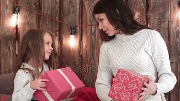 Mãe e uma linda menina segurando presentes de Natal e tentando adivinhar o que está dentro — Vídeo de Stock