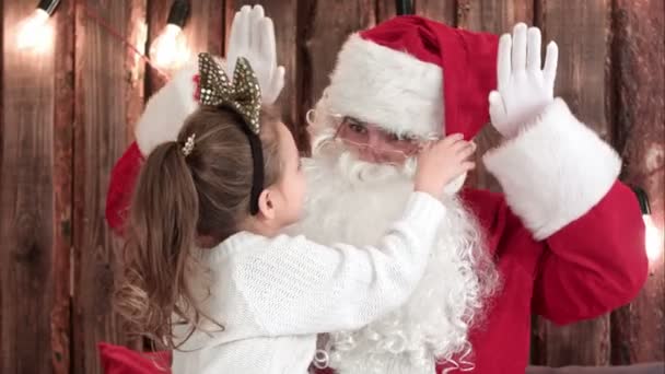 Menina bonito jogar com Santas barba sentado em seu colo — Vídeo de Stock