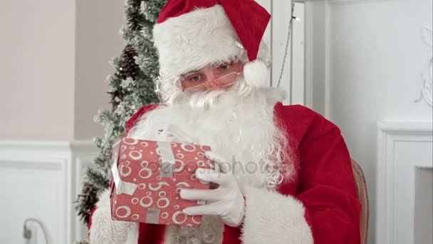 Santa Claus en su taller de Navidad firmando regalos para niños — Vídeo de stock