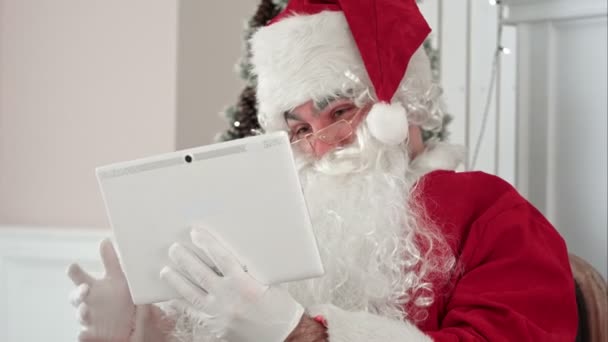 Radosny Święty Mikołaj sprawdzanie świąteczne e-maile od dzieci na jego cyfrowy tablicowy — Wideo stockowe