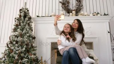 Neşeli genç anne ve kızı komik xmas selfies yapma ve dilleri gösterilen