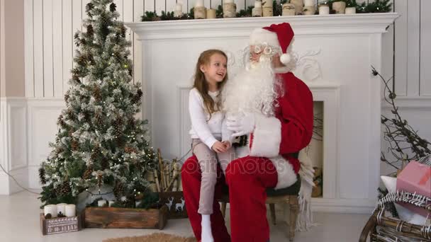 Linda niña cantando una canción de Navidad sentada en el regazo de Santa Claus — Vídeos de Stock