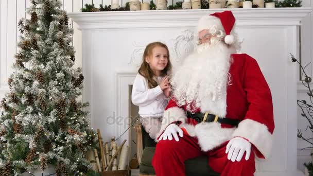 Sonriente y tímida chica compartiendo sus sueños de Navidad con Santa — Vídeo de stock