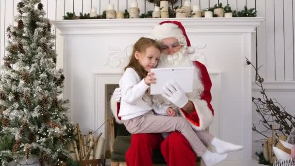 Feliz niña mostrando sorprendida Santa presenta en la tableta — Vídeo de stock