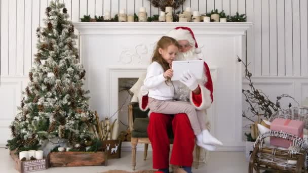 Little girl sitting with serious Santa Claus using tablet — Stock Video