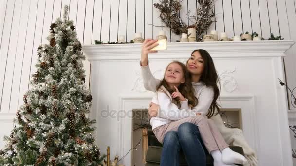 Fröhliche junge Mutter und ihre Tochter machen komische Weihnachtsselfies und zeigen Zungenschläge — Stockvideo