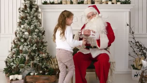 Красивая маленькая девочка преподносит Санта Клаусу рождественский подарок — стоковое видео