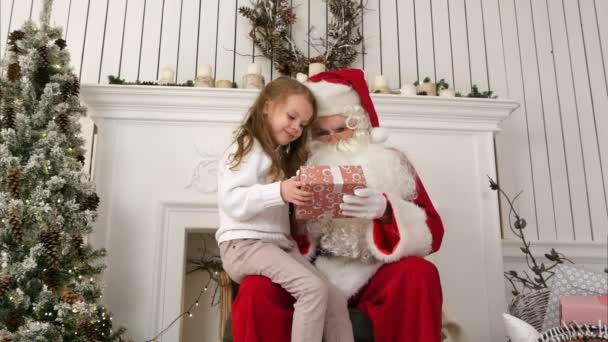 Litlle girl unwrapping her present together with Santa Claus — Stock Video