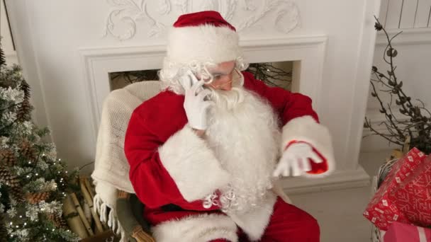 Санта-Клаус разговаривает по телефону, желая счастливого Рождества — стоковое видео