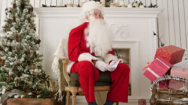 Nevetve Santa ül egy széken, karácsonyi műhelyében — Stock videók