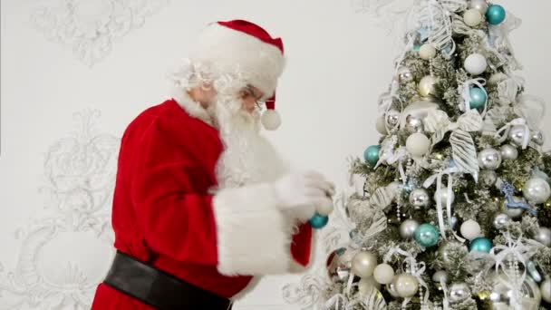 Weihnachtsmann schmückt Weihnachtsbaum mit Christbaumkugeln — Stockvideo