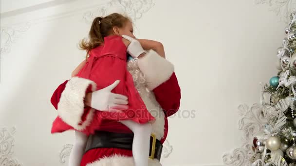 Santa Claus ayudando a la niña a colgar bolas en la parte superior del árbol de Navidad — Vídeos de Stock