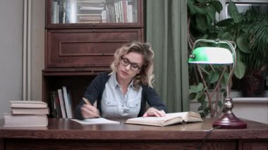 Bir masada oturan ve notları bir kitap yazma gözlüklü genç öğrenci