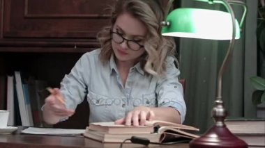 Raporunu masada yeşil lamba ile çalışan, kitaplar gidiş ve kahve içme bardaklarda meşgul öğrenci