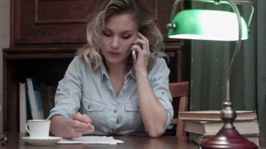 İş telefonda konuşurken ve notlar masasında yapma genç kadın konsantre