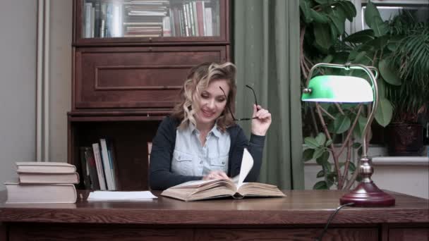 Sorridente giovane donna felicemente annuendo la testa mentre cerca informazioni in un libro — Video Stock