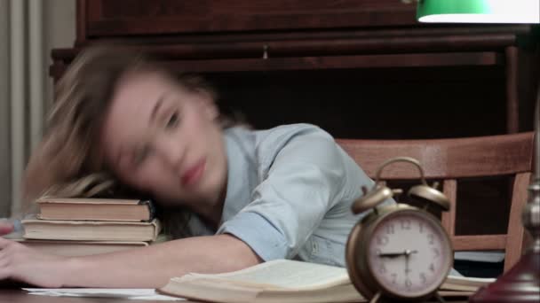 Tired female taking a nap on a pile of books and being woken up by an alarm — Stock Video