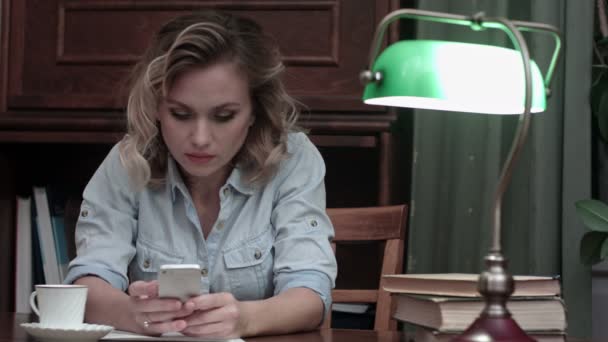 심각한 젊은 여 자가 그녀의 직장에 앉아서 그녀의 전화에 메시지를 입력 — 비디오
