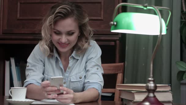웃는 젊은 여성이 직장에서 휴식 하 고 그녀의 휴대 전화에 문자 메시지를 입력 — 비디오