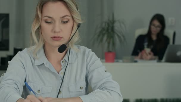 Upptagen Callcenter agent använder digitala surfplatta på ett samtal på hennes arbetsplats — Stockvideo